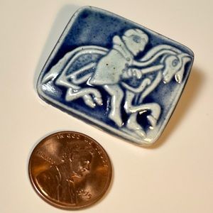 Knight on horse blue glaze over white (tile? Porcelain? Clay?) rectangular pin